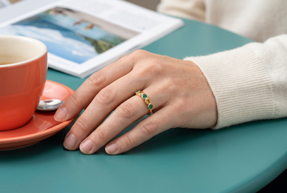 Emerald Dawn ring concept worn beside a coral coffee cup