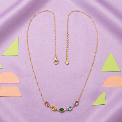 Gold-tone necklace with five colorful accents on lilac fabric and peach lime shapes
