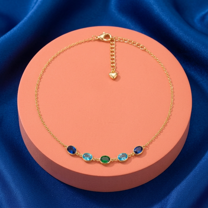Complete blue green five-oval necklace on coral pedestal against cobalt fabric