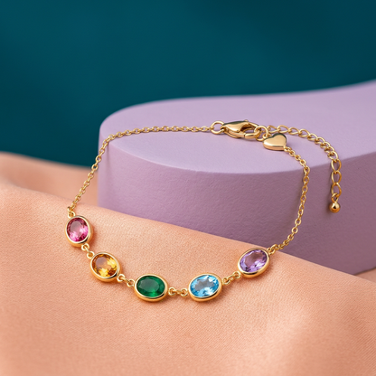 Five-color oval bracelet with gold-tone chain on peach fabric and lilac pedestal